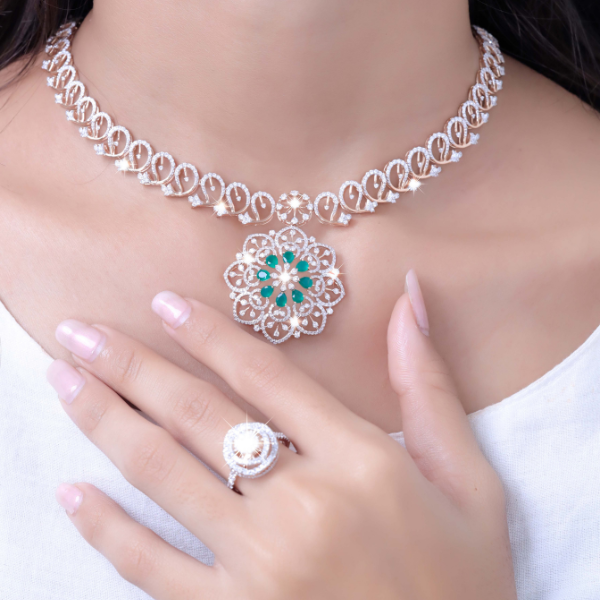 A diamond necklace with a flower pendant set with emeralds, and a matching halo ring